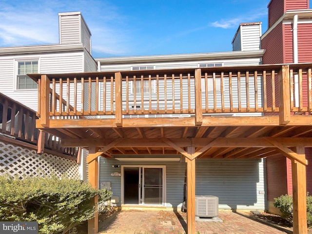 rear view of house with a deck, central AC unit, and a chimney