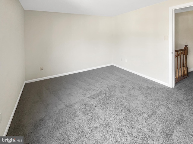 empty room featuring baseboards and dark carpet