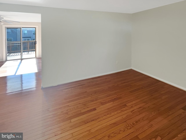 empty room featuring a ceiling fan, baseboards, and hardwood / wood-style flooring