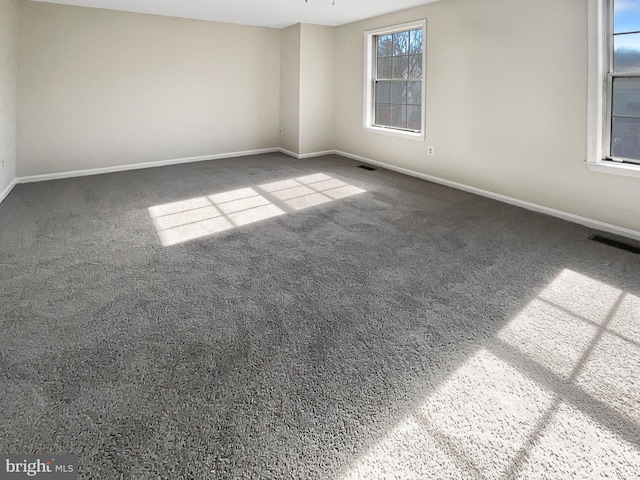 carpeted empty room featuring baseboards and visible vents