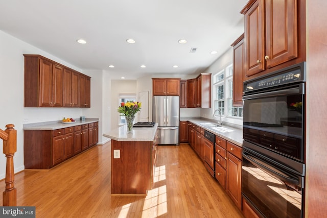 kitchen featuring a center island, light wood-style flooring, stainless steel appliances, and a sink