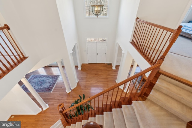 stairs featuring baseboards, a high ceiling, an inviting chandelier, and wood finished floors