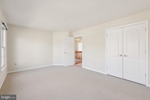 unfurnished bedroom with baseboards, light carpet, and a closet