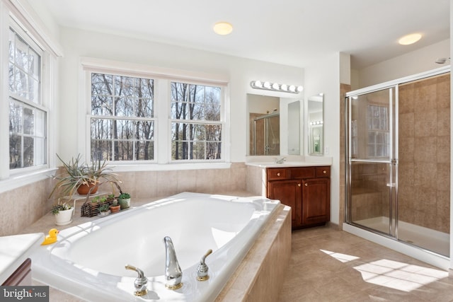 bathroom with a wealth of natural light, a garden tub, a stall shower, and vanity