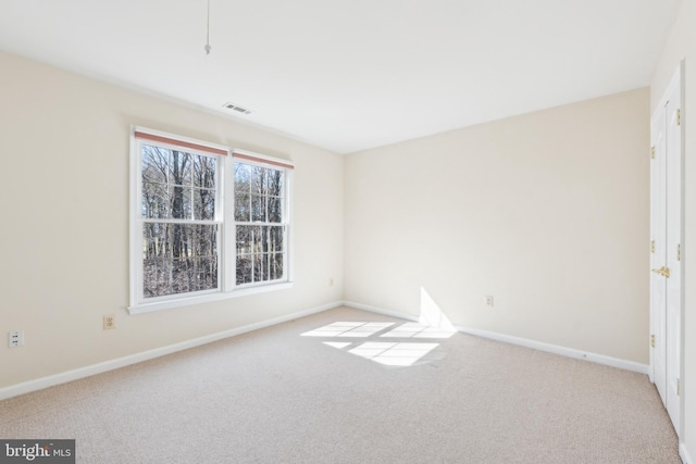 spare room featuring carpet flooring, visible vents, and baseboards