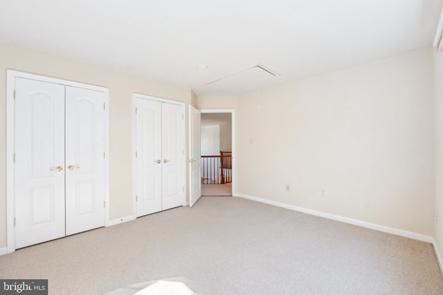 unfurnished bedroom featuring baseboards, multiple closets, and carpet