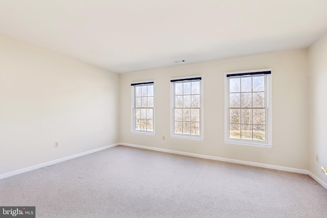 spare room featuring baseboards and light carpet