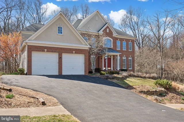 view of front of house with brick siding, stucco siding, driveway, and a garage