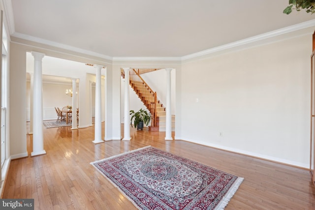 interior space with baseboards, decorative columns, light wood-style floors, crown molding, and a notable chandelier