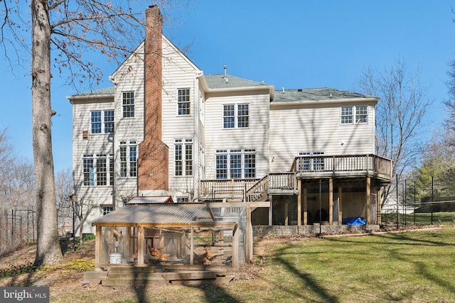 rear view of property featuring a lawn, a chimney, and a deck