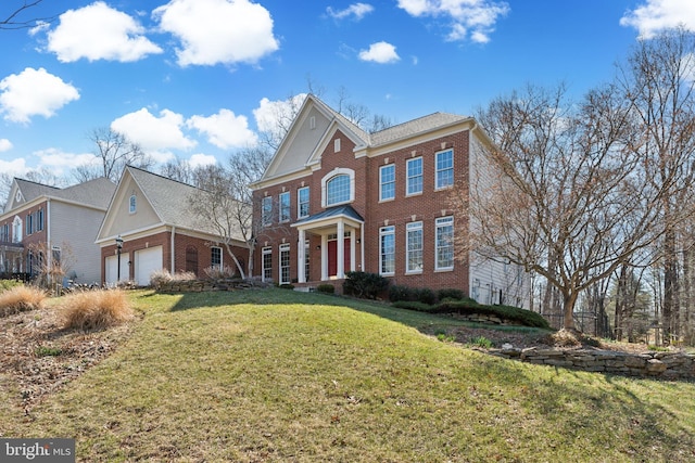 colonial-style house featuring brick siding, an attached garage, and a front yard