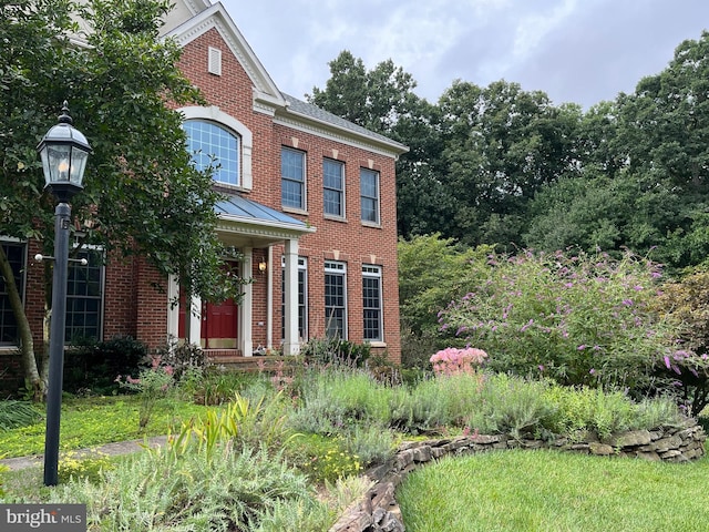 view of front of house featuring metal roof, brick siding, and a standing seam roof