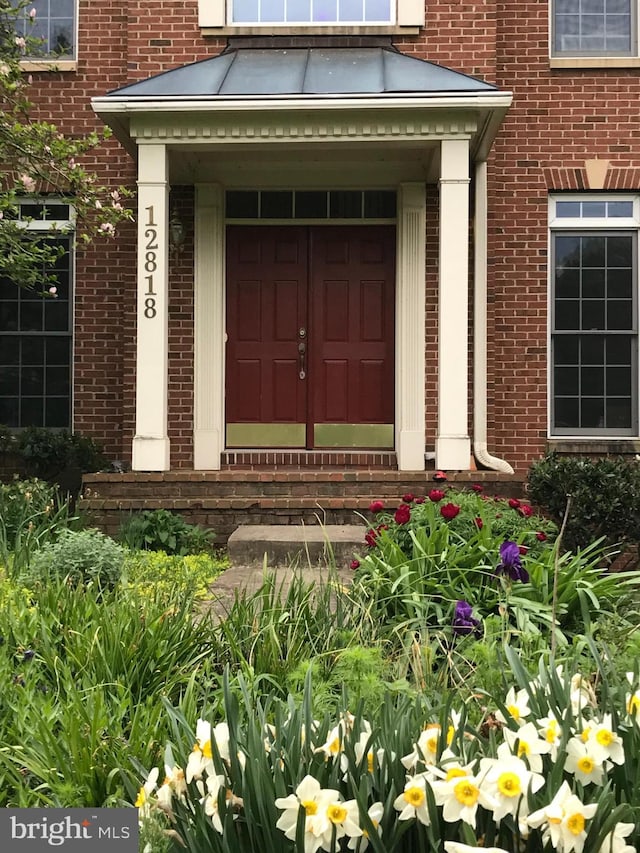 entrance to property featuring a standing seam roof, brick siding, and metal roof