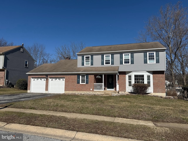 view of front of house featuring brick siding, an attached garage, a front yard, covered porch, and driveway