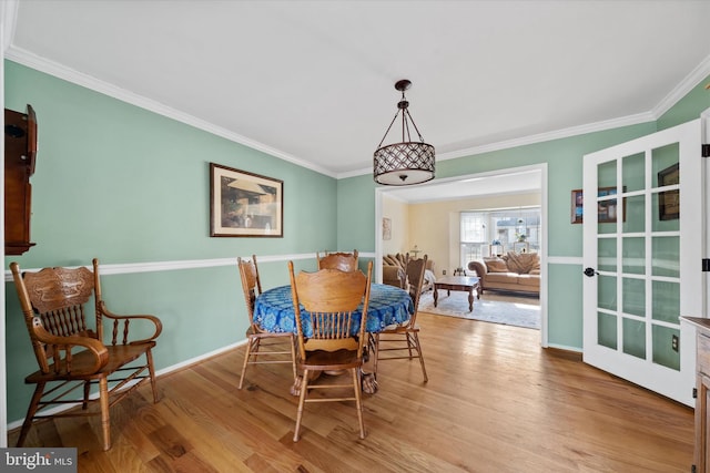 dining room featuring crown molding, wood finished floors, and baseboards