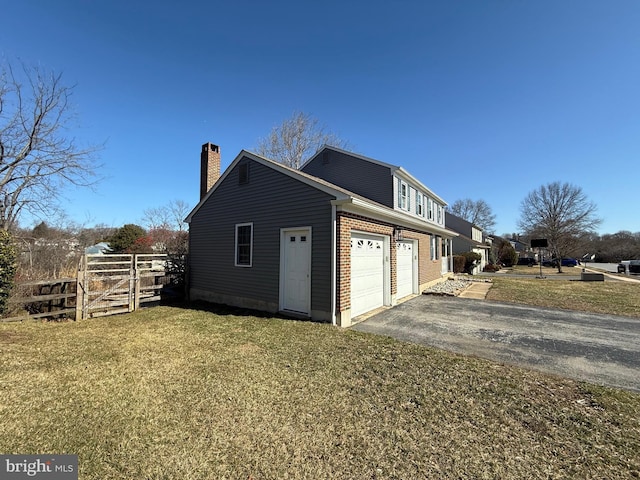 view of home's exterior with fence, a chimney, a garage, aphalt driveway, and brick siding