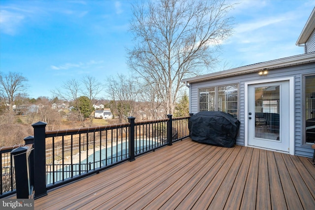 wooden deck featuring a fenced in pool and a grill