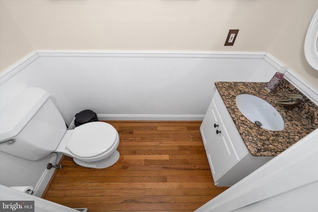 bathroom featuring wainscoting, toilet, vanity, and wood finished floors