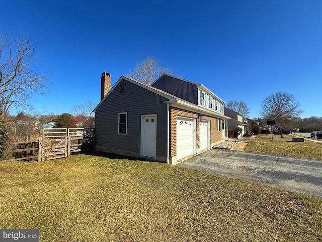 view of side of home featuring brick siding, fence, a lawn, a chimney, and driveway