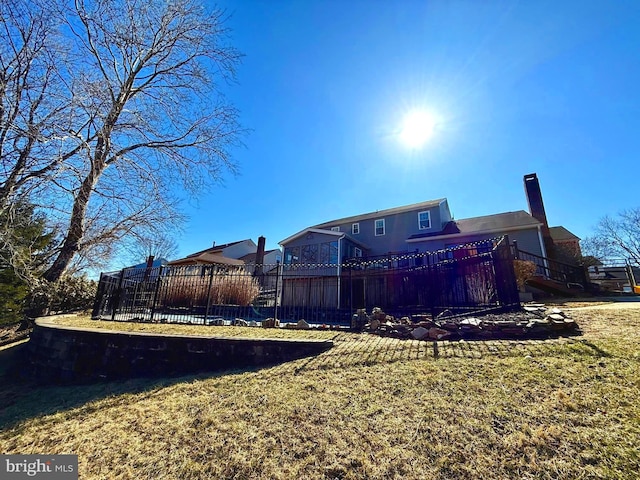 rear view of property featuring a lawn, a chimney, and fence