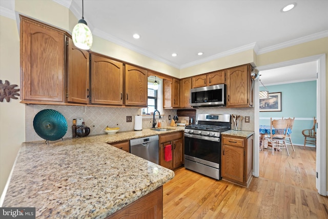 kitchen featuring brown cabinets, ornamental molding, a sink, stainless steel appliances, and light wood-style floors