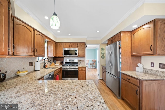 kitchen featuring backsplash, crown molding, light wood-style flooring, appliances with stainless steel finishes, and a sink