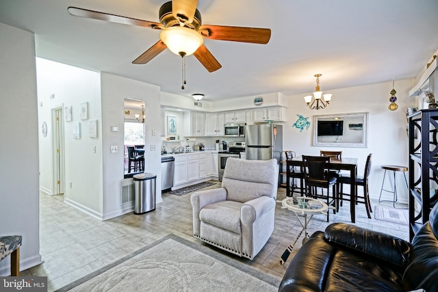 living room featuring baseboards and ceiling fan with notable chandelier