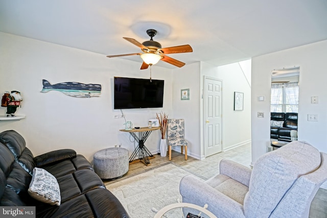 living area featuring baseboards and ceiling fan