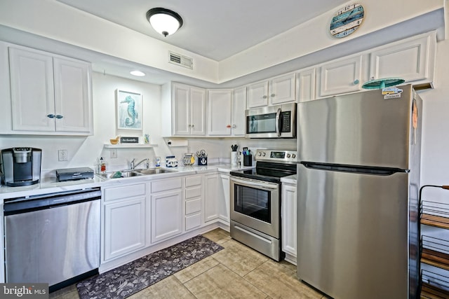 kitchen with visible vents, light countertops, white cabinets, stainless steel appliances, and a sink