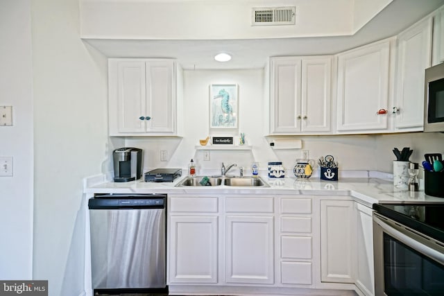 kitchen featuring visible vents, light countertops, appliances with stainless steel finishes, white cabinets, and a sink