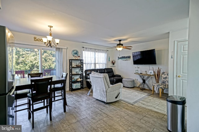 living room featuring ceiling fan with notable chandelier, baseboards, and wood tiled floor