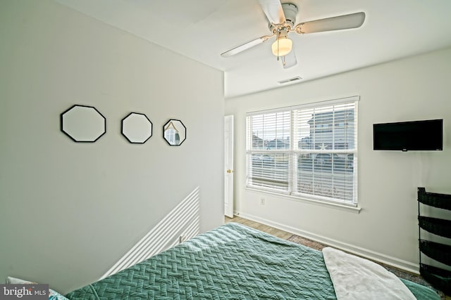 bedroom with visible vents, baseboards, wood finished floors, and a ceiling fan