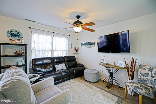 living room with wood finished floors, visible vents, and ceiling fan