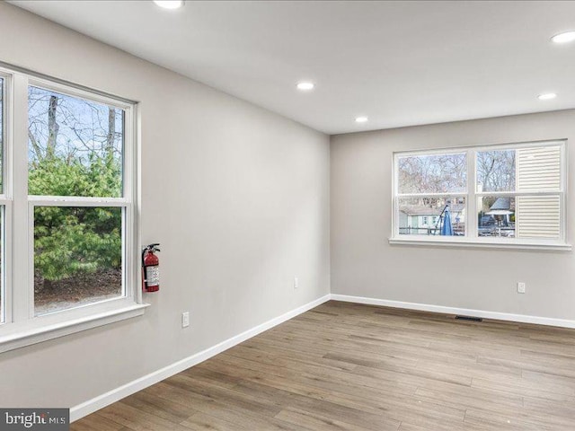 unfurnished room featuring baseboards, a healthy amount of sunlight, and wood finished floors