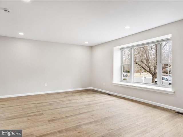 spare room featuring recessed lighting, light wood-style flooring, and baseboards