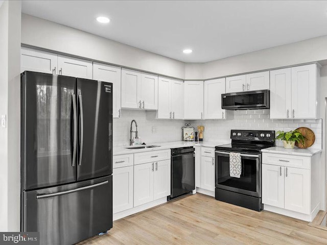 kitchen with a sink, tasteful backsplash, white cabinetry, stainless steel appliances, and light wood finished floors