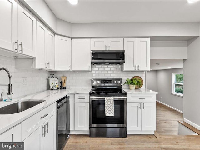 kitchen with baseboards, light wood-style flooring, a sink, stainless steel appliances, and white cabinetry