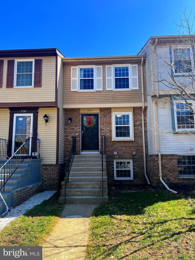 view of property with brick siding and a front yard