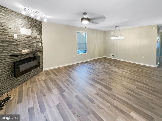 unfurnished living room featuring visible vents, a ceiling fan, wood finished floors, a fireplace, and baseboards