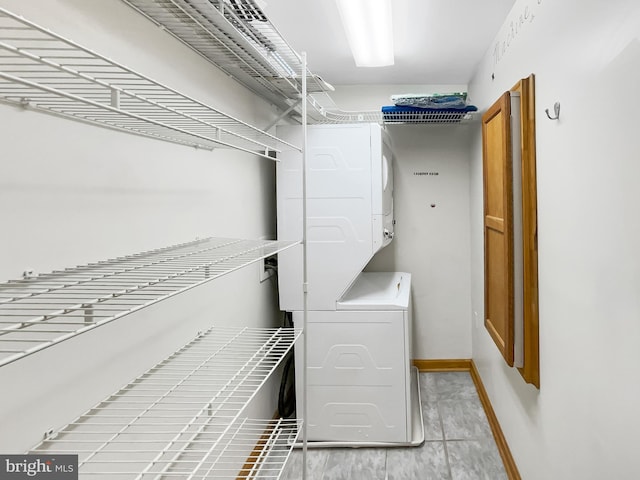 washroom featuring laundry area, baseboards, and stacked washer and clothes dryer