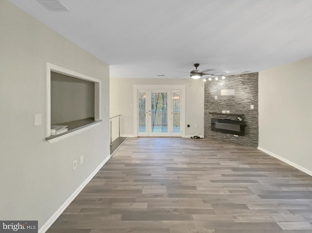 unfurnished living room featuring visible vents, wood finished floors, a large fireplace, baseboards, and ceiling fan