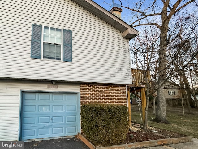 view of side of home with brick siding, a chimney, and a garage