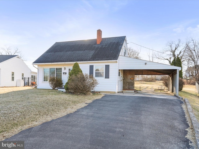 view of front facade with an attached carport, roof with shingles, driveway, and a chimney