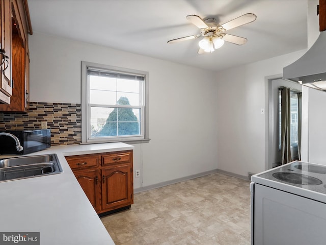 kitchen featuring a sink, backsplash, white range with electric stovetop, wall chimney range hood, and light countertops