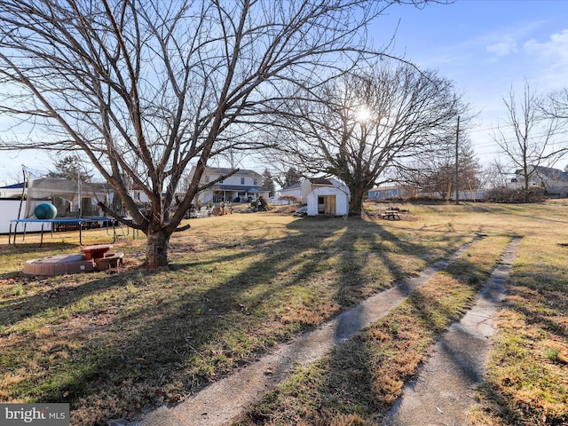 view of yard featuring an outbuilding, a storage unit, and a trampoline