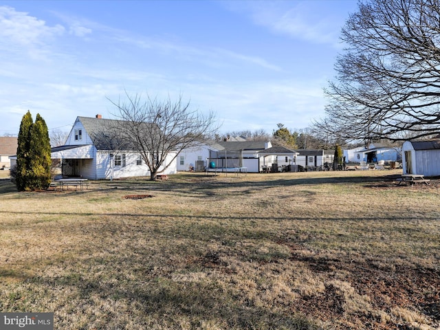 view of yard with a storage unit, an outbuilding, a trampoline, and fence