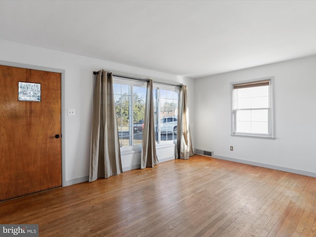 unfurnished room featuring visible vents, baseboards, and hardwood / wood-style floors