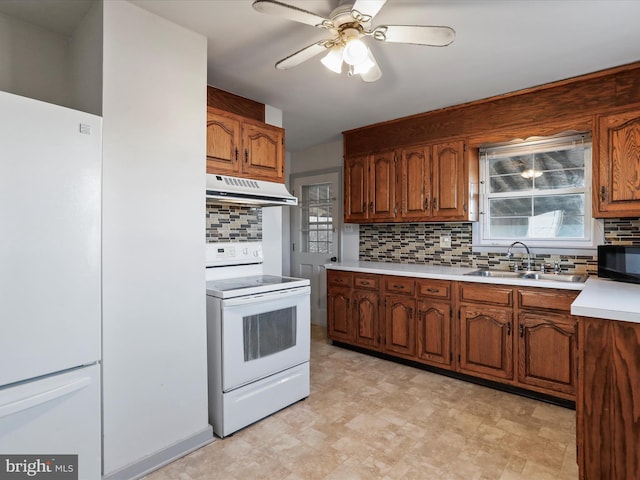 kitchen featuring white appliances, a sink, light countertops, under cabinet range hood, and tasteful backsplash