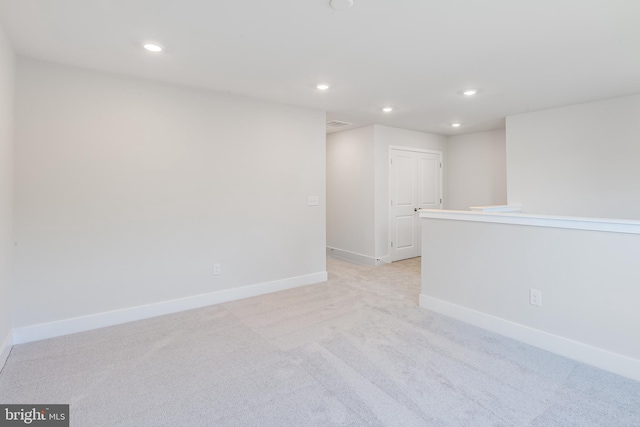 spare room with recessed lighting, light colored carpet, and baseboards