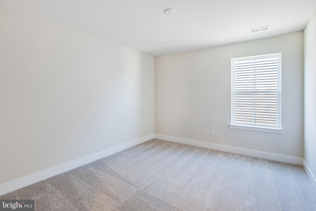 spare room with visible vents, light carpet, and baseboards